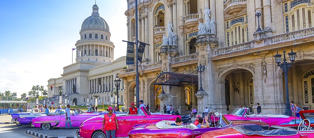 Havana, Cuba – 16 December, 2019: Vintage colorful taxis waiting for tourists close to National Capitol Building (El Capitolio) on Paseo del Prado street in front of Gran Havana theater