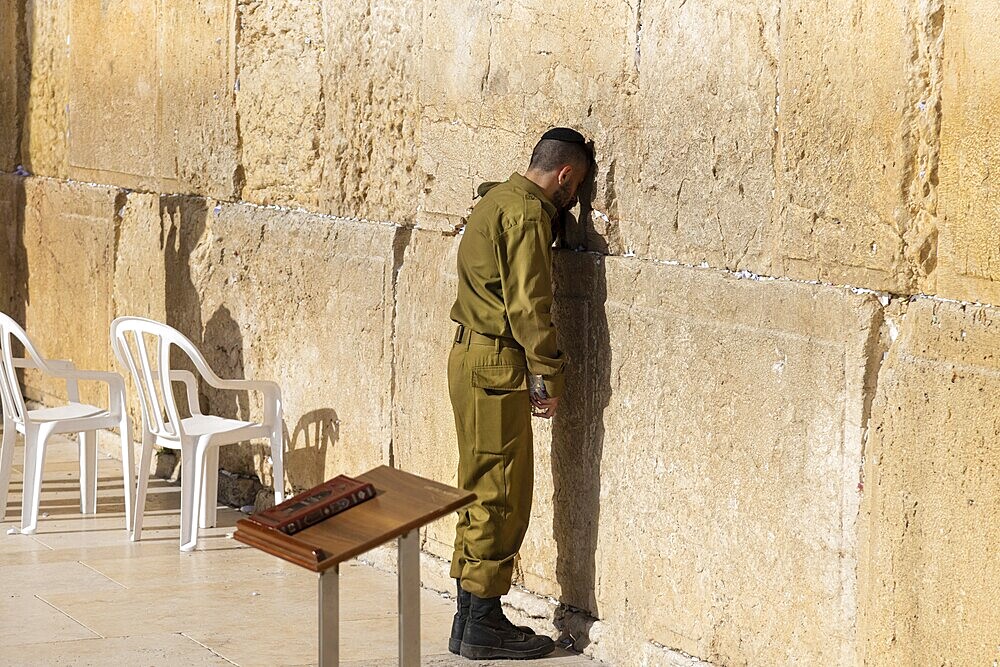 Jerusalem, Israel, 15 April, 2022: Israeli soldier praying in front of Sacred Western Wall in Jerusalem Old City Jewish Temple, Asia