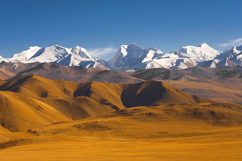 Peaks of the himalayas poke through the beautiful natural landscape of the barren mountainous terrain at the himalayan border between Nepal and Tibet