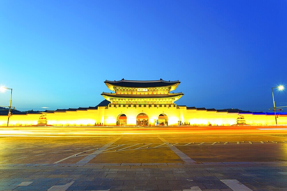 Long exposure car lights leaving a straight light trail in front of Gwanghwamun main entrance gate to Gyeongbokgung Palace in historic part of downtown on a clear, twilight night in Seoul, South Korea, Asia