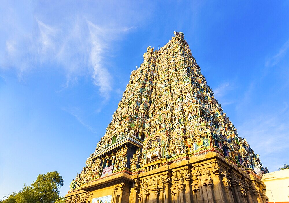 West tower gateway of Meenakshi Amman Temple covered in colourful statues of gods on a blue sky day at Madurai in south Indian state of Tamil Nadu, India, Asia