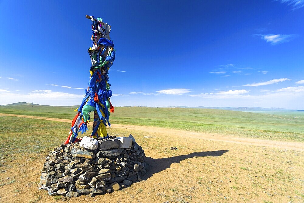 Small Buddhist stone stupa with prayer flags stands on the vast steppe in countryside Mongolia