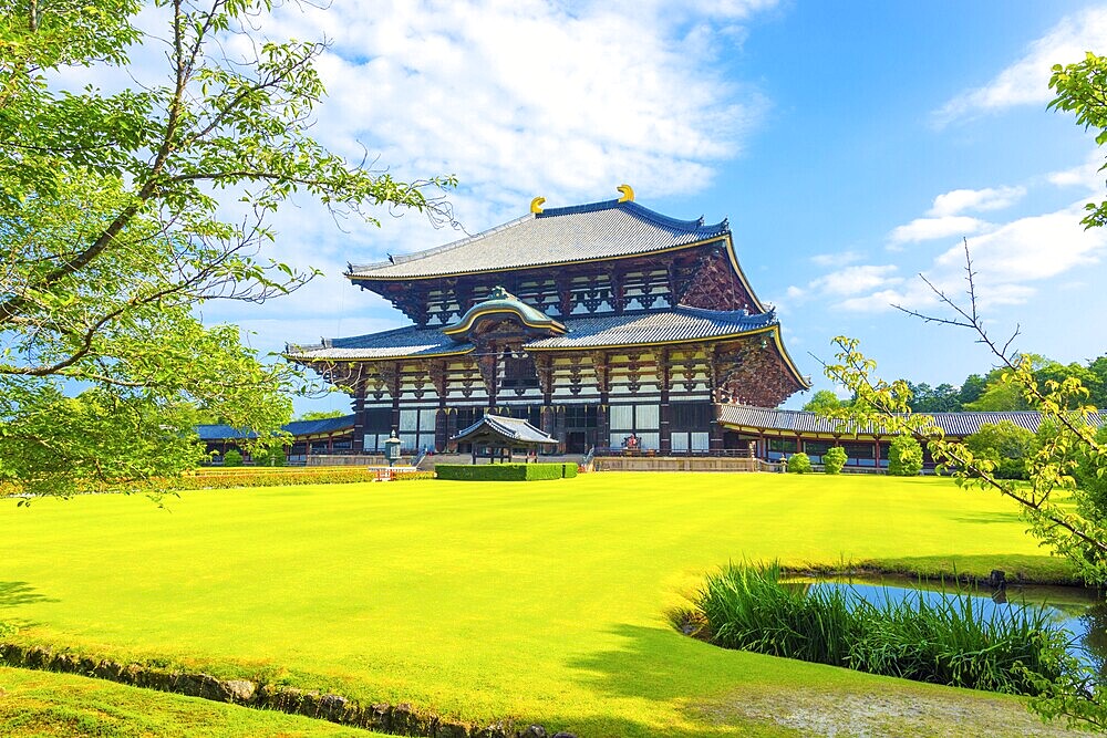 Wide green lawn in front entrance facade on grounds of main Great Buddha Hall, Daibutsuden, on a beautiful, blue sky summer morning at Todai-ji temple in Nara, Japan. Horizontal