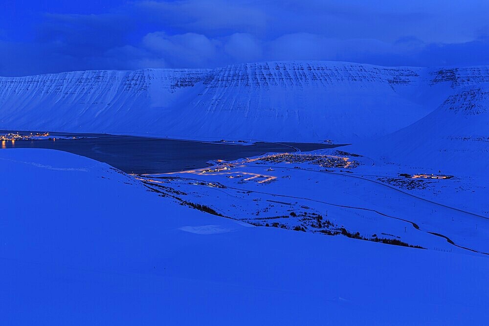 Fjord landscape at dusk, snow, illuminated city, mountains, Isafjördur, Westfjords, Iceland, Europe