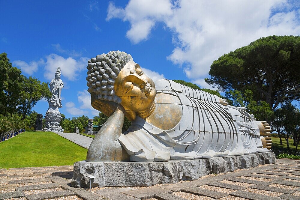 Monumental reclining Buddha statue in a green and peaceful park under a clear blue sky, Bacalhôa, Bacalhoa Buddha Eden, Quinta dos Loridos, largest oriental garden in Europe, Bombarral, Oeste, Centro, Portugal, Europe