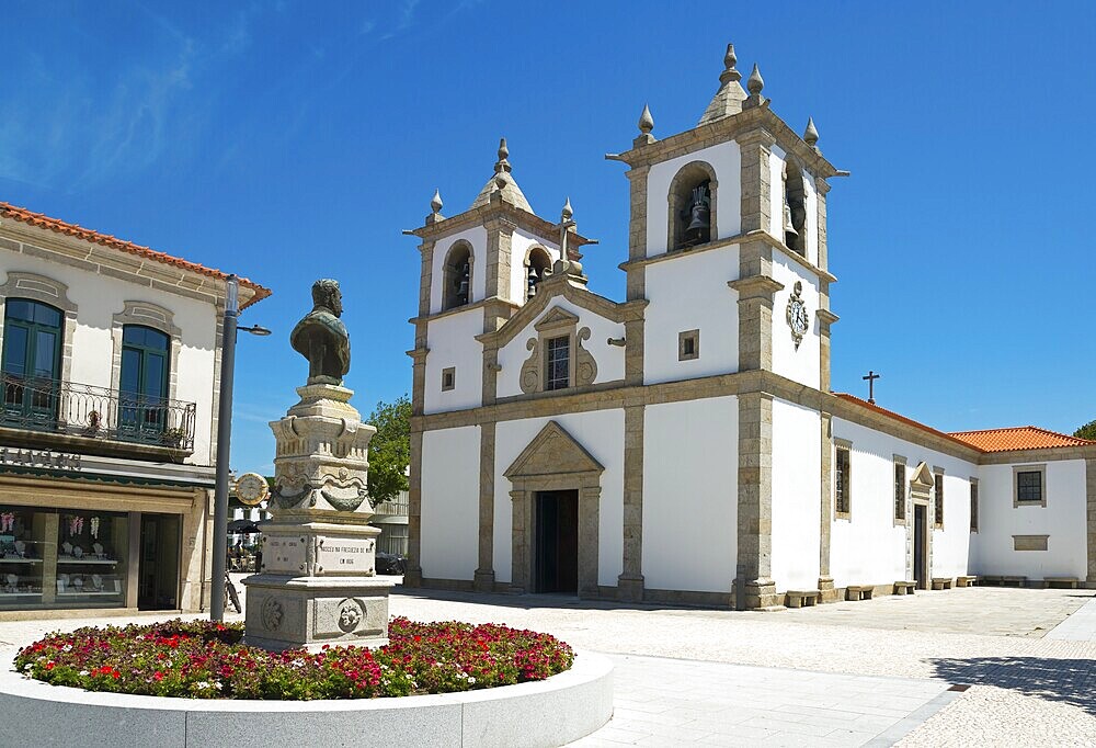 A church with a double tower stands on a sunny square with a flower bed, Igreja Matriz de Esposende, in front of it a monument by António Rodrigues Sampaio, Esposende, União das Freguesias de Esposende, Marinhas e Gandra, Norte, Portugal, Europe