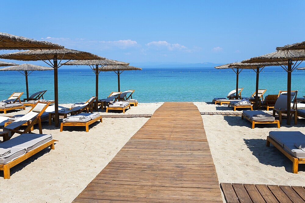 Wooden walkway leads to a sunlit beach with deckchairs and parasols by the clear sea, Lago Seaside Experience, Golden Beach, Pallini, Palioúri, Kassandra, Chalkidiki, Halkidiki, Central Macedonia, Greece, Europe