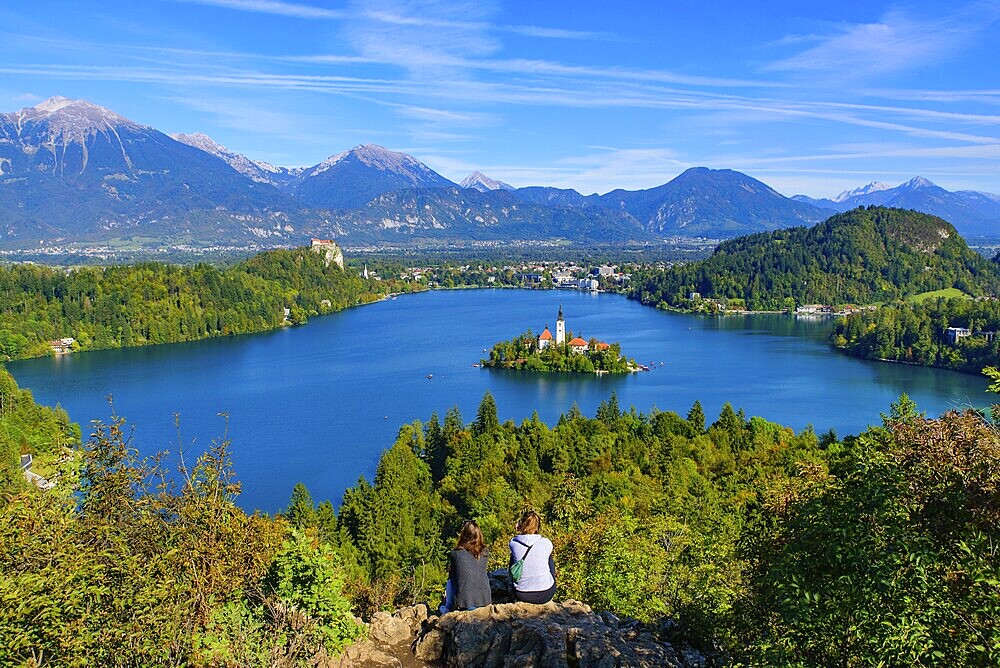 Two people at Osojnica Hill watching the view of Bled Island and Lake Bled, a popular tourist destination in Slovenia