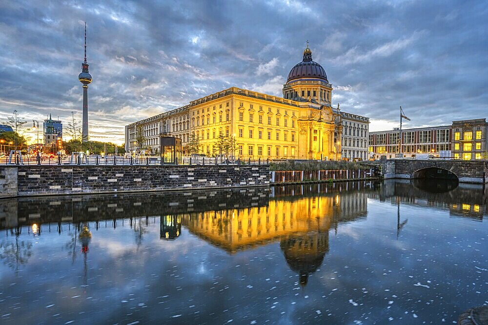 The rebuilt Berlin City Palace with the television tower and some dark storm clouds at dawn