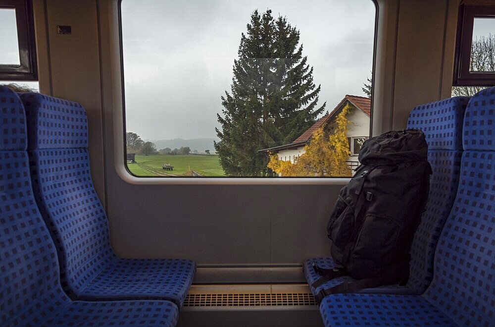 German train interior with a rucksack on the seats and a bavarian landscape view on the window