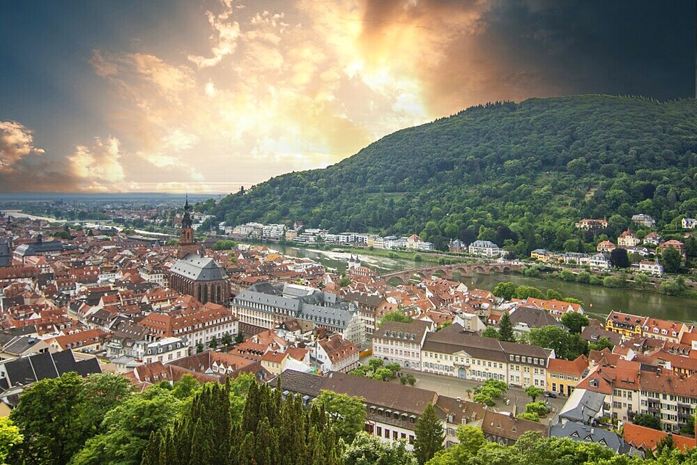View over an old town with churches in the evening at sunset. This town lies in a river valley of the Neckar, surrounded by hills. Heidelberg, Baden-Württemberg, Germany, Europe
