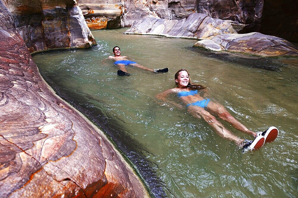Young couple floats at the canyon of Wadi Mujib, Jordan, Asia