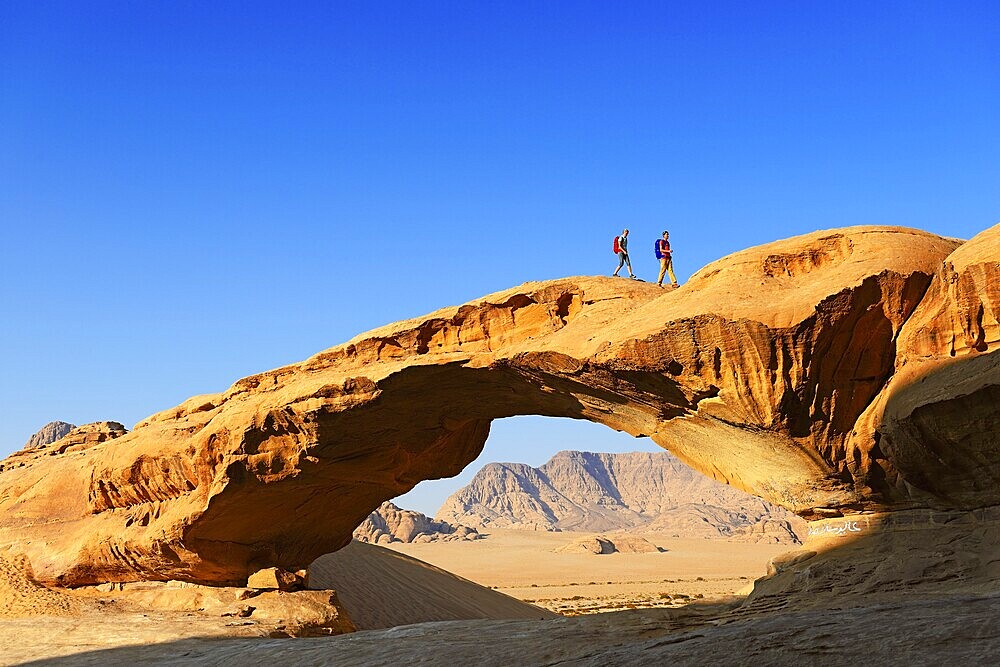 Couple hiking at Rock-Arch named Al Kharza, Wadi Rum, Jordan, Asia
