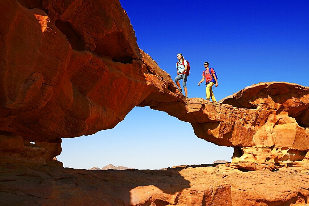 Couple hiking at Rock Arch, Al Borg Alsagheer, Wadi Rum, Jordan, Asia