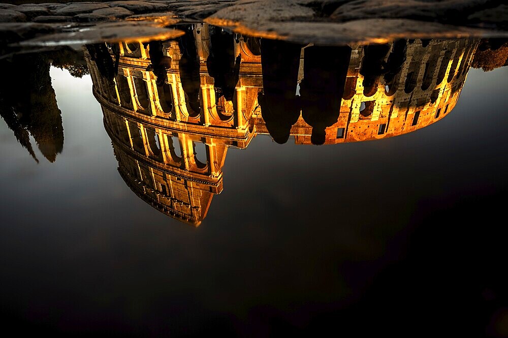 Romantic image of the Colosseum, reflected in the water in golden light, Rome