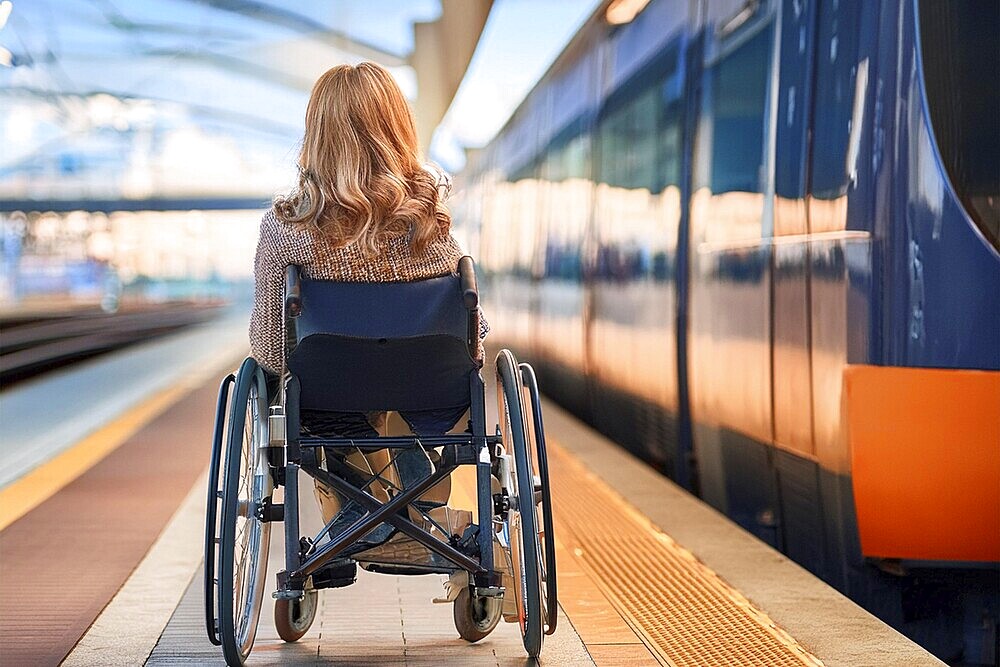 Woman in a wheelchair waiting for the train on the platform, surrounded by the warmth of the sunset, ai generated, KI generated, AI generated
