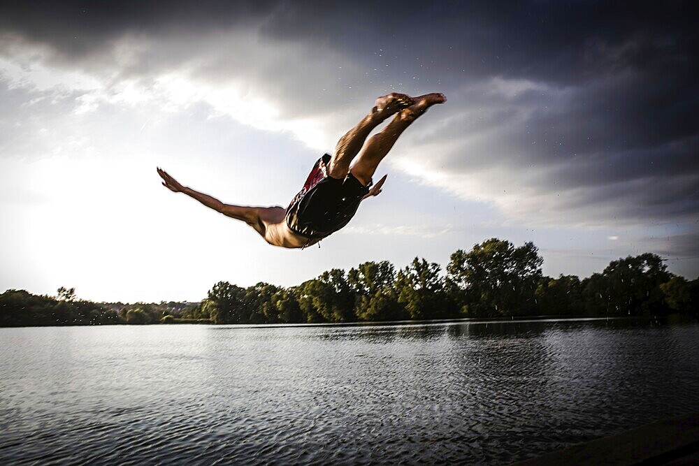 A young man plunging into water from the riverside, Germany, Europe
