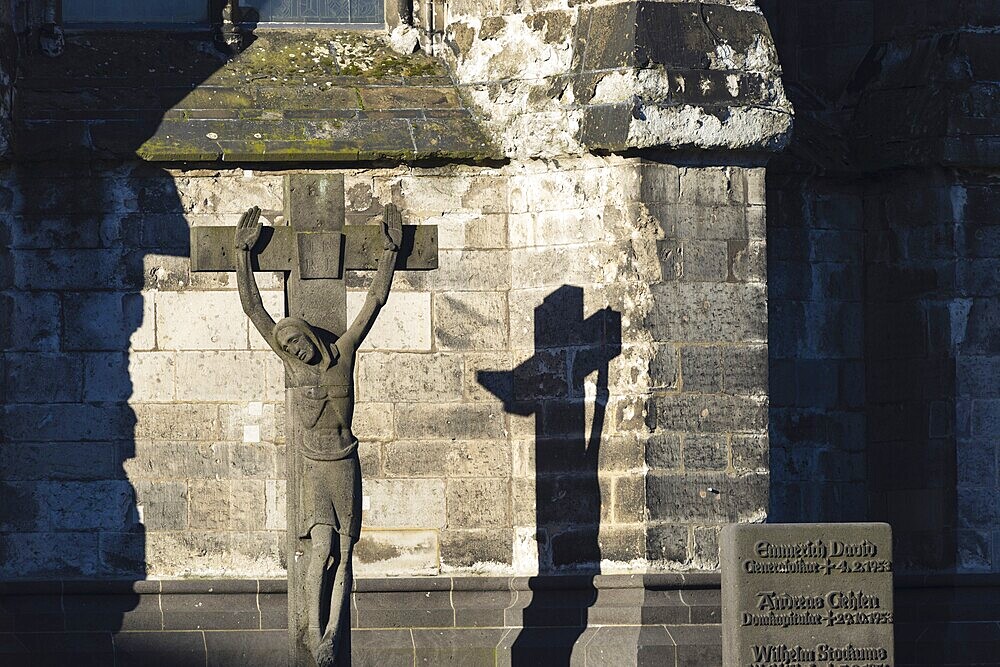 Stone cross with shadow cast, cathedral cemetery near Cologne Cathedral, Cologne, North Rhine-Westphalia, Germany, Europe