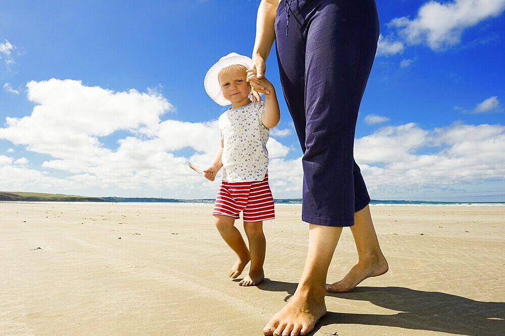 Little girl holding her mother's hand walking along a beach, Brittany, France, Europe