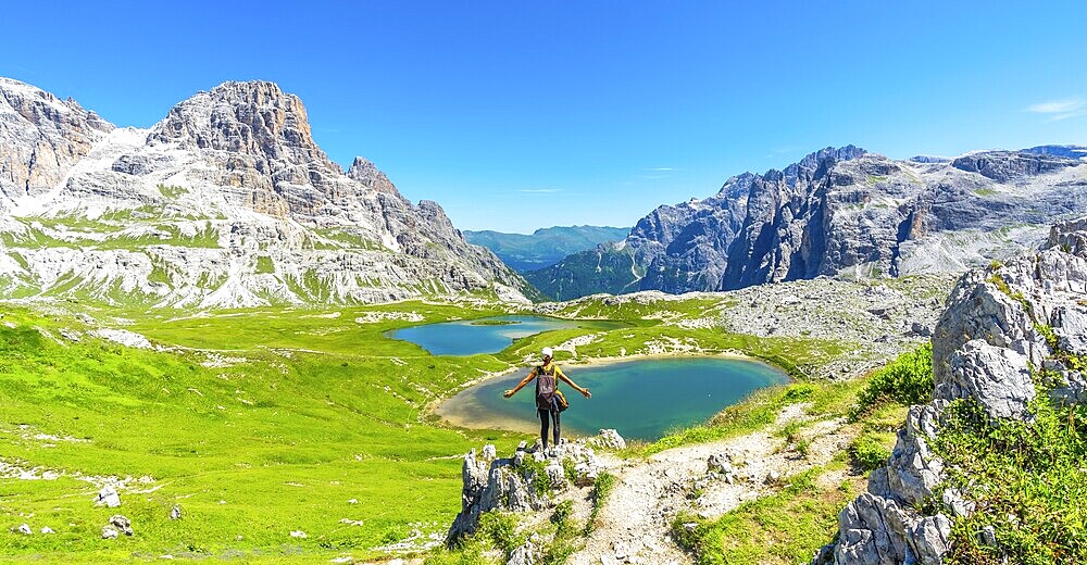 Tourist enjoying the scenic view of tre cime di lavaredo and alpine lakes on a sunny summer day in the italian dolomites. Laghi dei Piani