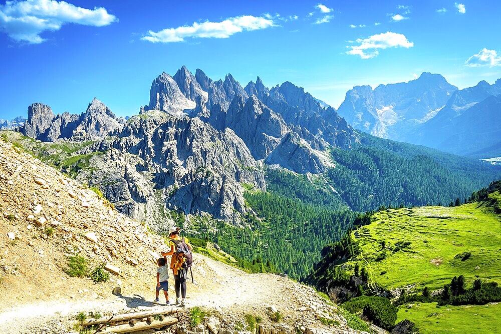 Tourists enjoying breathtaking views while hiking on a scenic trail in tre cime di lavaredo, dolomites, italy, during a sunny summer day