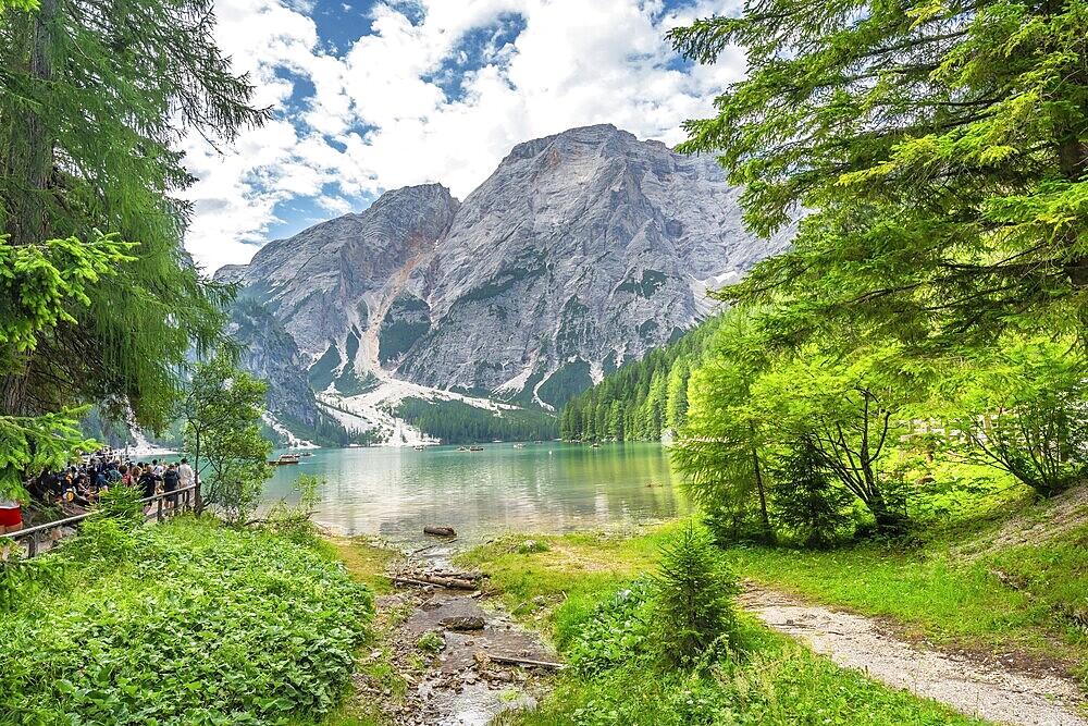 Tourists enjoying the landscape at lake braies, also called pragser wildsee, with the seekofel mountain in the background, in the dolomites, south tyrol, italy
