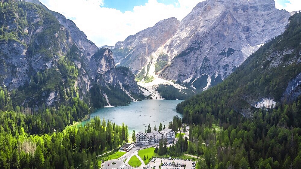 Stunning aerial view of lake braies with the iconic seekofel mountain and a charming hotel nestled amidst the lush greenery of the italian dolomites in summer