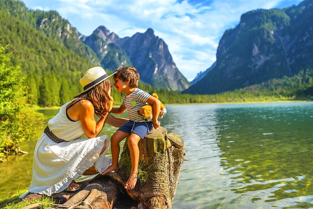 Mother and son sharing a tender moment while enjoying the breathtaking scenery of lake dobbiaco in the italian dolomites during their summer vacation