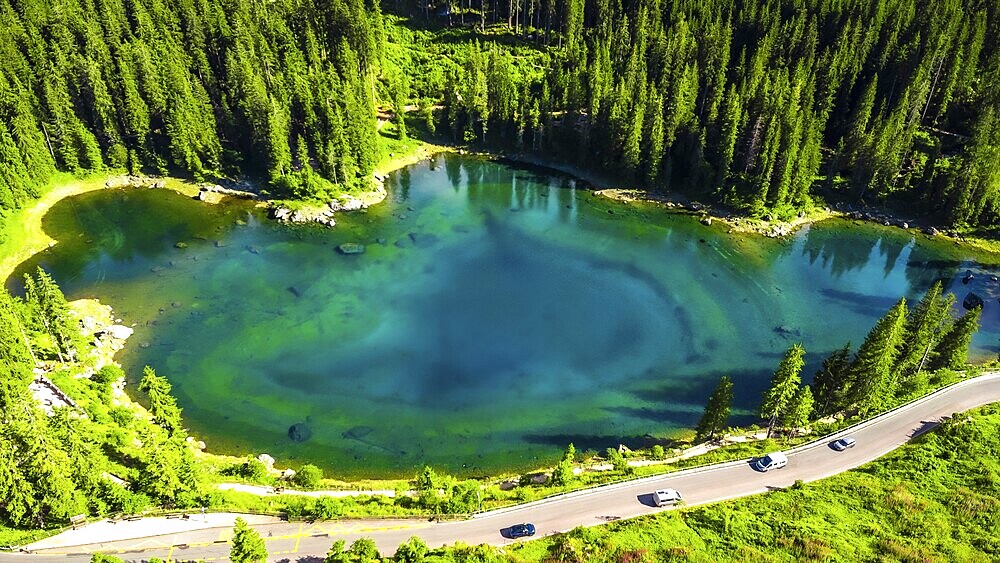 Aerial view capturing the stunning turquoise waters of alpine lake karersee reflecting the surrounding dolomites and coniferous forest