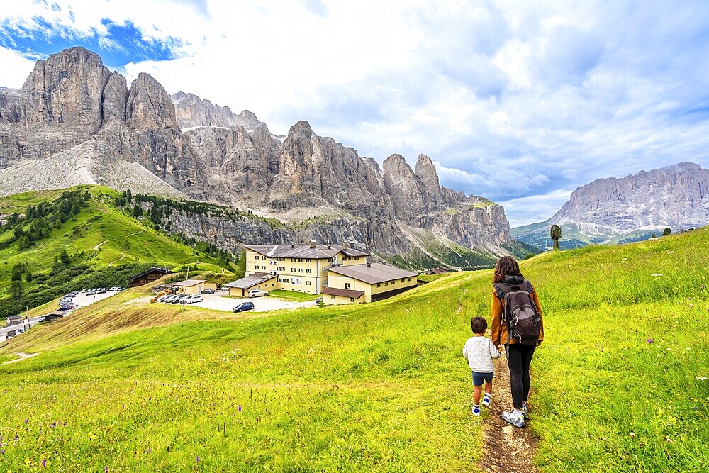 Tourists enjoying a summer hike through the stunning dolomites near gardena pass, italy, surrounded by breathtaking landscapes and vibrant meadows