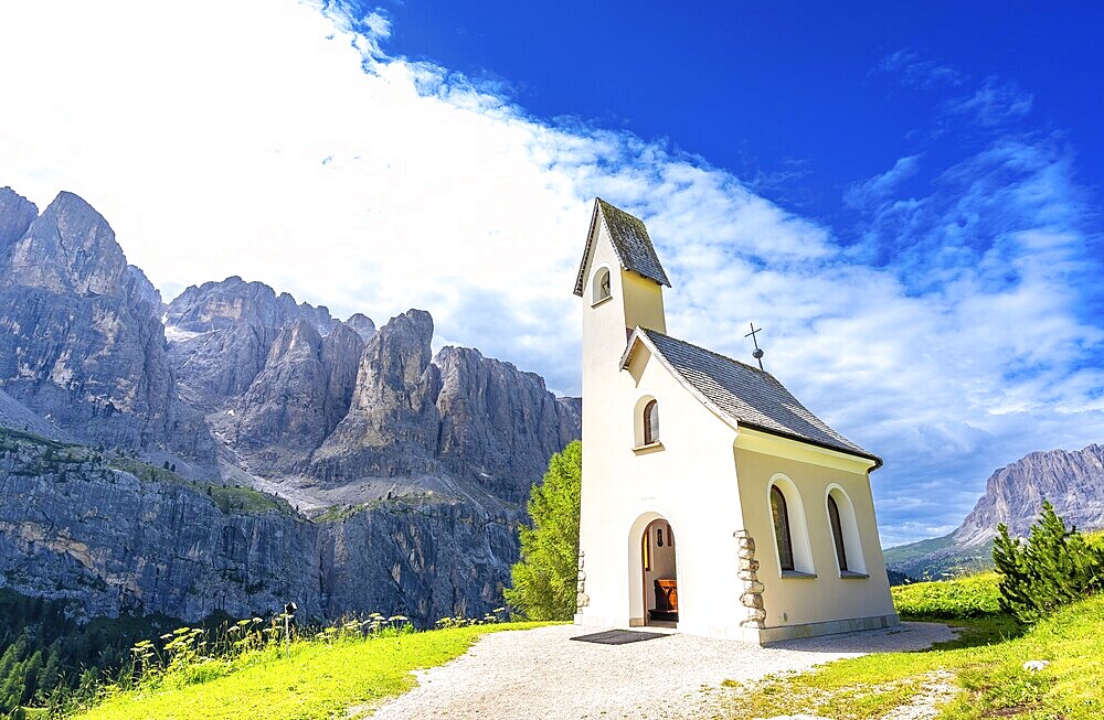 Scenic view of a charming church nestled in the italian dolomites, with the breathtaking peaks creating a stunning backdrop under a vibrant blue sky