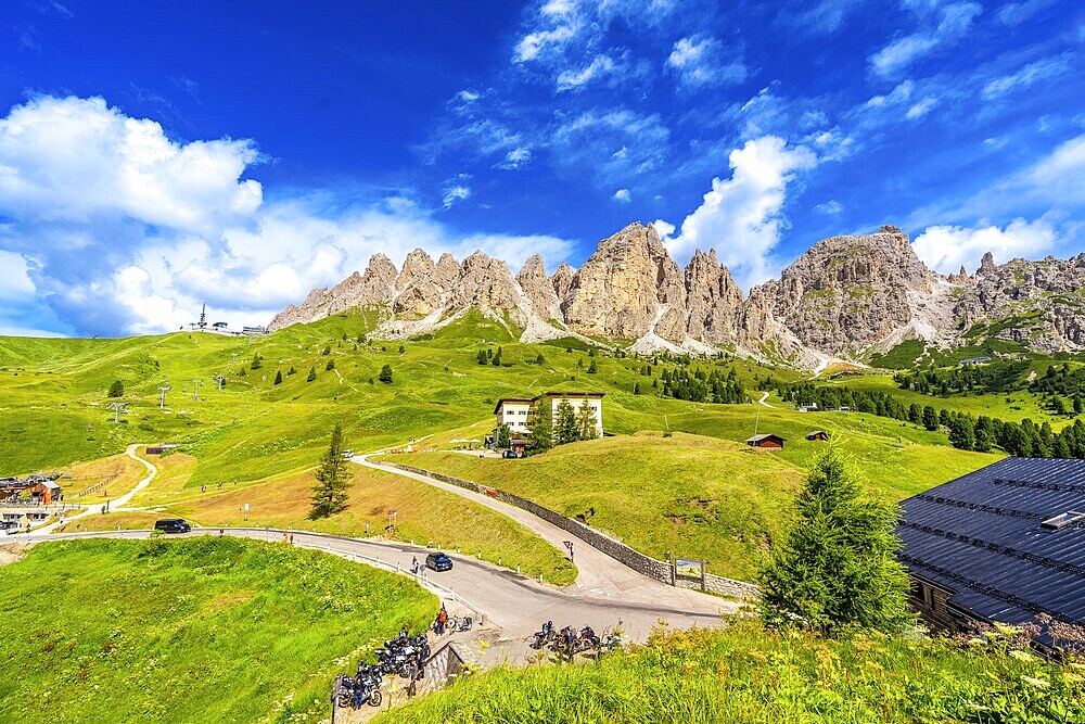 Breathtaking view of the majestic dolomites group mountains and the winding road of passo gardena during a sunny summer day