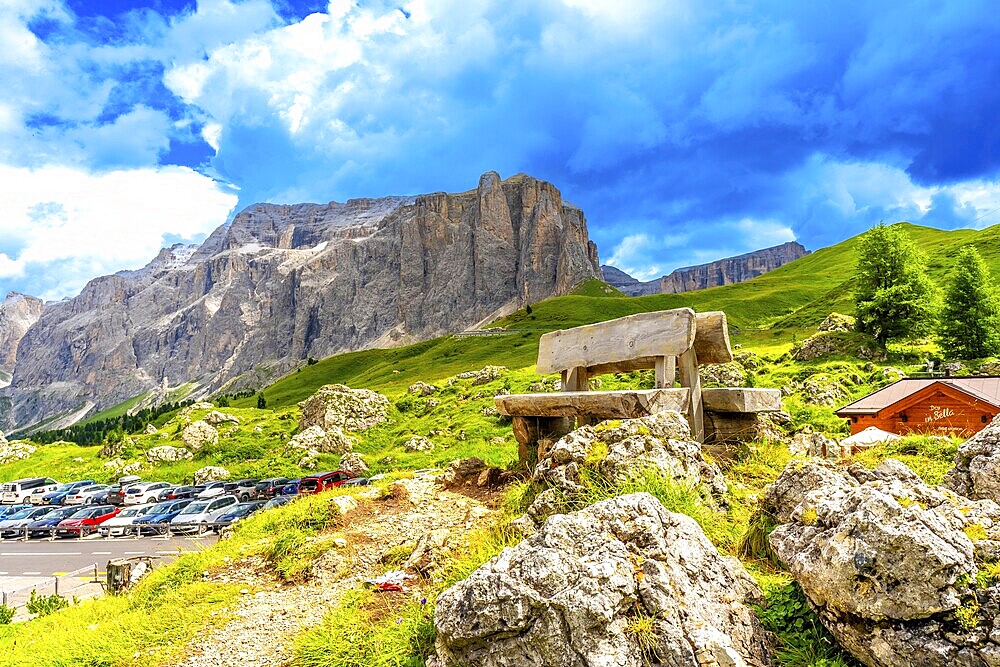 Weathered wooden bench inviting rest while offering breathtaking views of sella pass in the italian dolomites