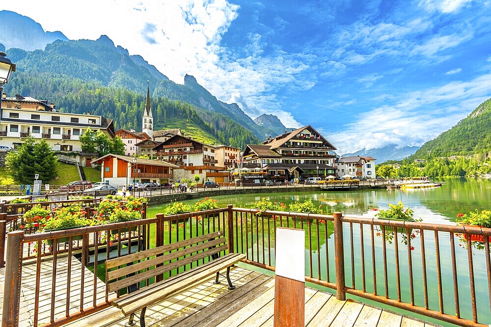 Tourists strolling along the picturesque shores of alleghe lake in the stunning dolomites on a beautiful summer day, enjoying nature's beauty