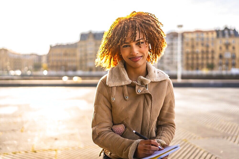 Beauty latin woman sketching on notebook sitting in the city