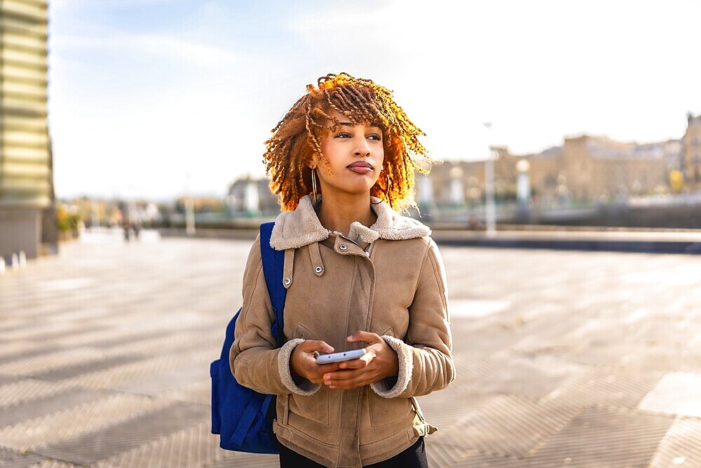 Beauty young latin woman using mobile phone to find a direction in the city