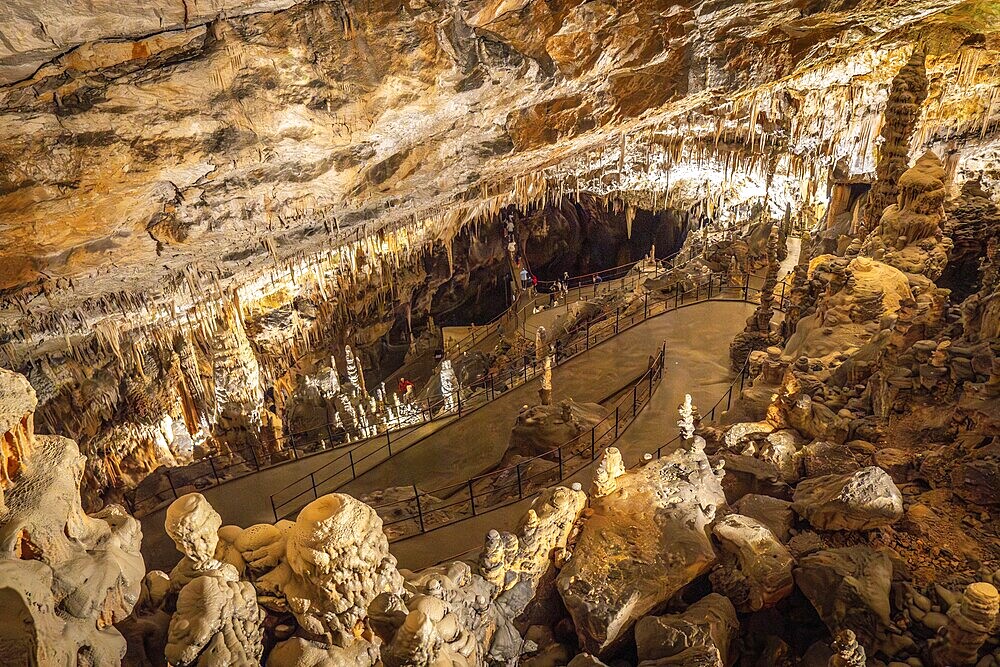 Tourists walking on illuminated footpath inside the famous postojna cave, a karst cave system near postojna, slovenia