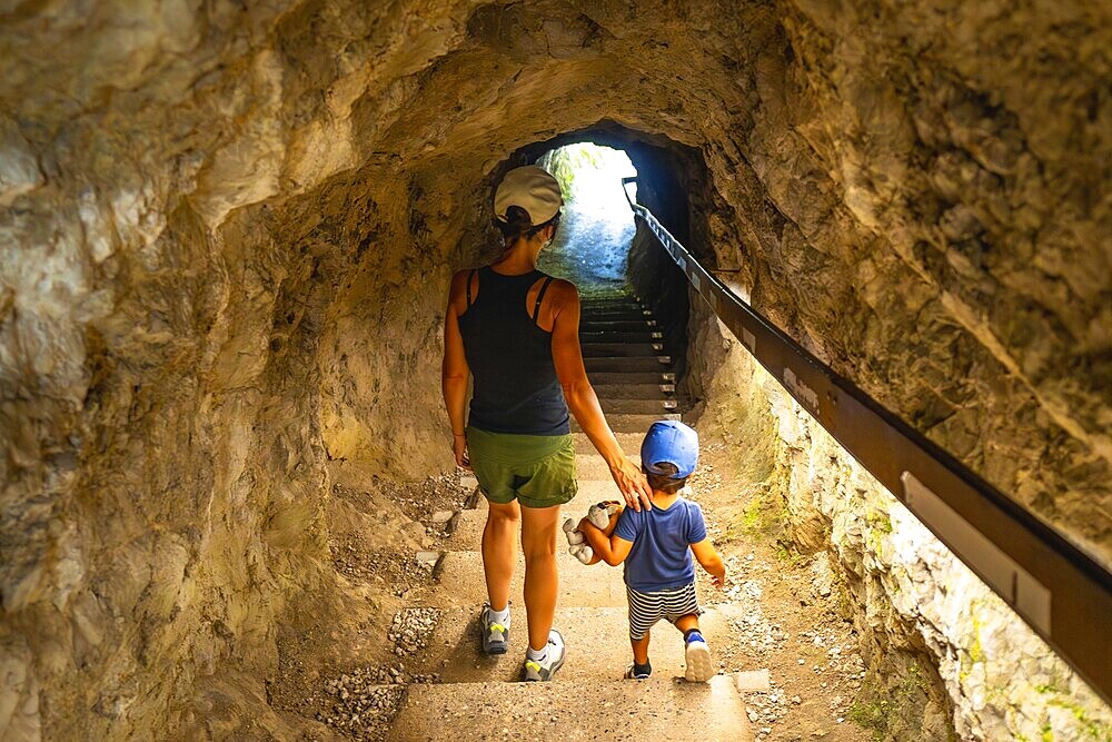 Mother and son walking up the stairs in a tunnel carved into the rock face at tolmin gorge in slovenia