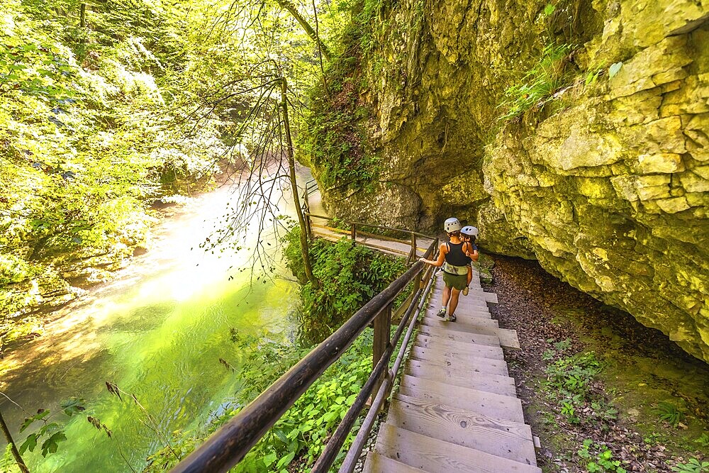 Tourists wearing helmets are walking down wooden stairs along the radovna river in vintgar gorge, a popular tourist destination near bled, slovenia
