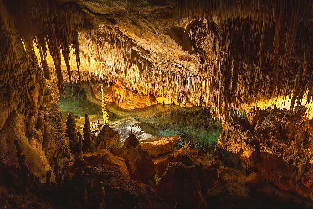 Illuminating stalactites reflecting in the turquoise waters of martel lake create a breathtaking subterranean spectacle in drach caves