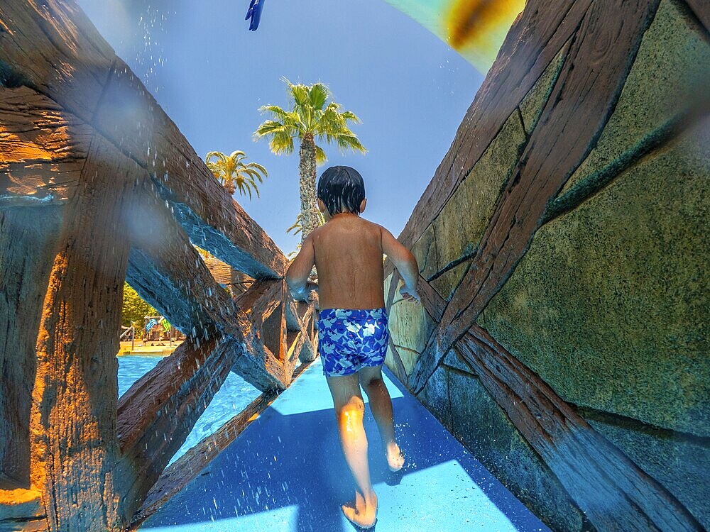 Child running through a water park during summer vacation in alicante, spain, enjoying the refreshing spray and the thrill of the water