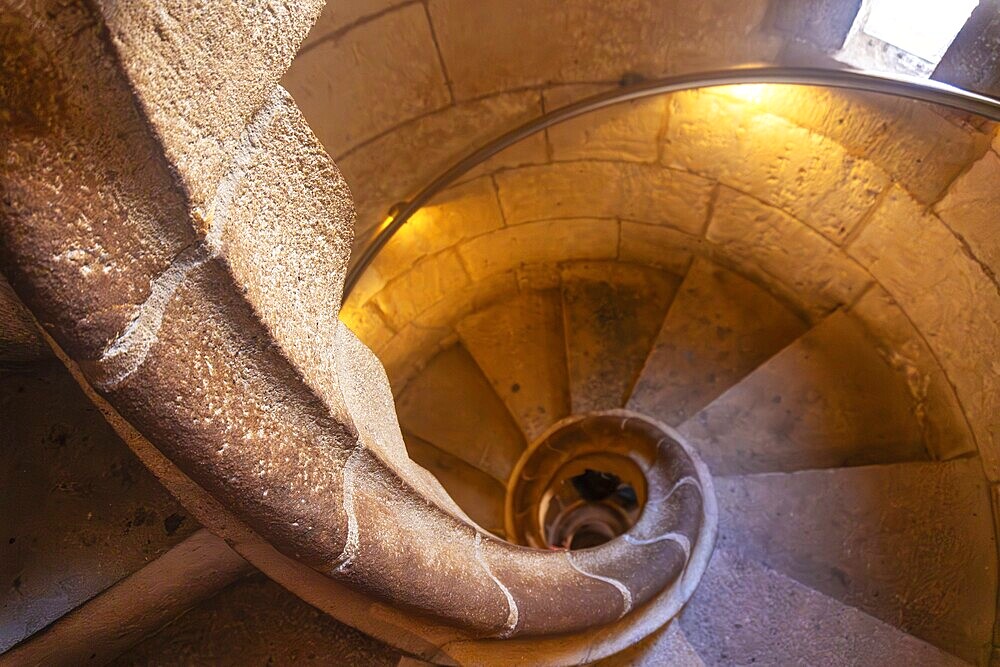 Warm light illuminating ancient stone spiral staircase descending into the depths of barcelona cathedral, a captivating architectural marvel