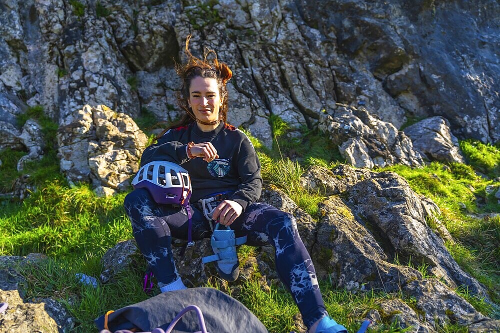 Young climber woman resting on a mountain after her climbing activity, checking her smartwatch