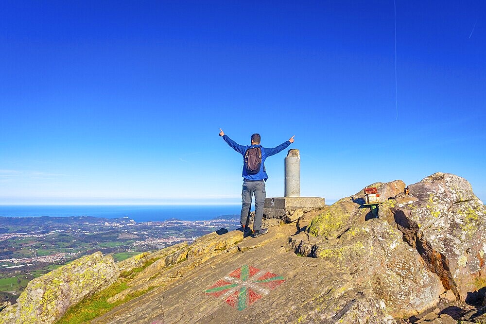A male hiker celebrating the climb to the top of Mount Adarra in Urnieta. Gipuzkoa, Basque Country