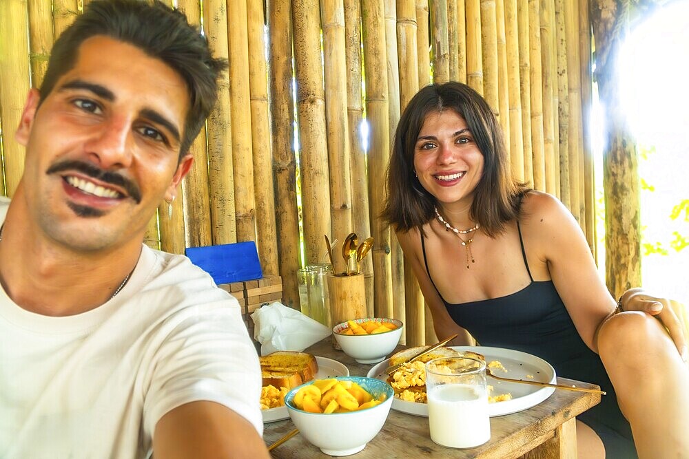Tourists having breakfast with mango and scrambled eggs in a bamboo hut during their holidays in siargao island, philippines