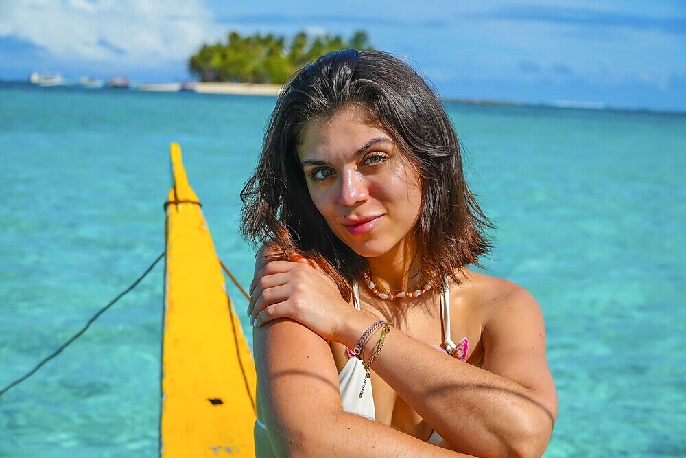 Young woman relaxing on traditional outrigger boat, enjoying the turquoise waters of daku island in siargao, philippines