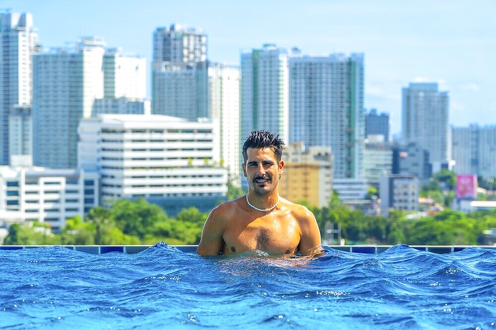 Tourist enjoying refreshing swim in rooftop infinity pool with breathtaking view of cebu city skyline, philippines