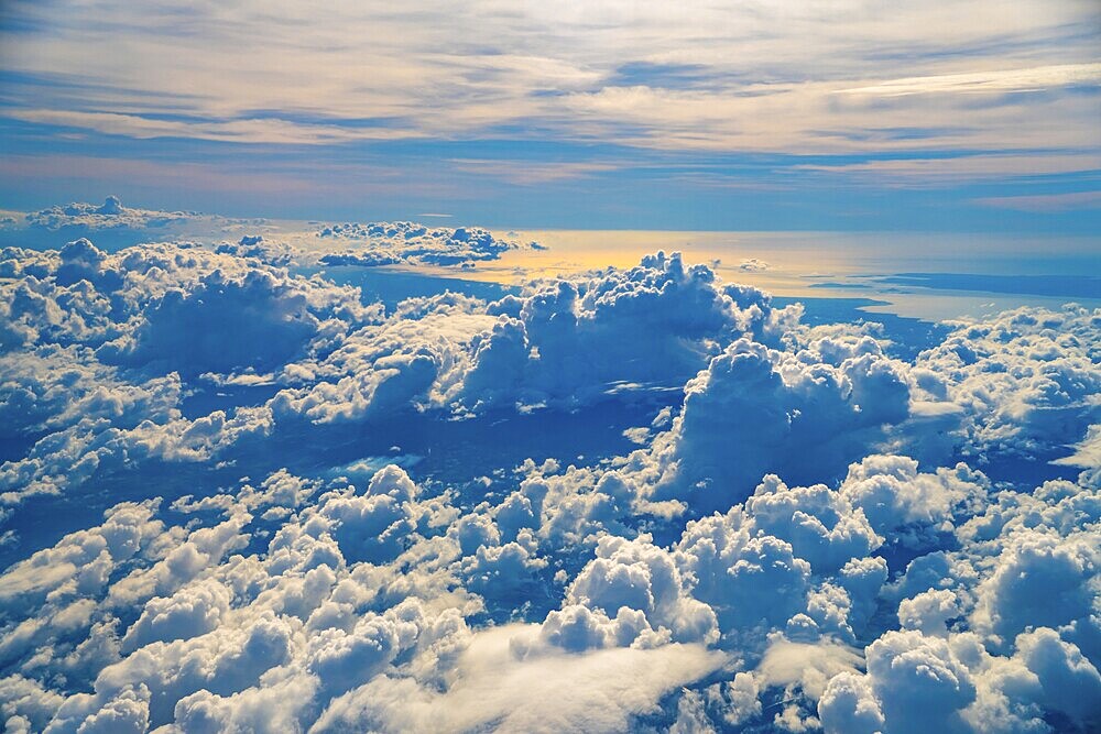 Golden hour sunlight illuminates a vast expanse of fluffy white clouds over coron island, philippines, creating a breathtaking aerial view