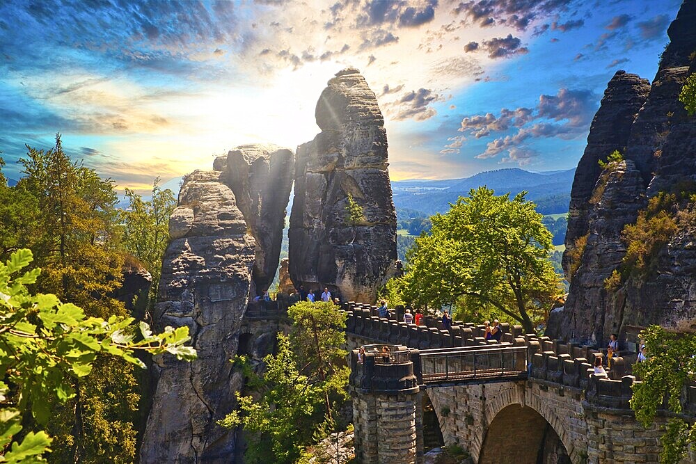 Stone Bastei Bridge connects imposing rocks at sunset, surrounded by lush trees, Elbe Sandstone Mountains, Saxon Switzerland, Saxony, Germany, Europe