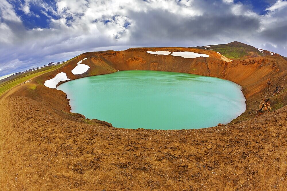 Krafla lake in the crater of an extinct volcano. Lake water bright green color. On the shores lie snowfields from last year